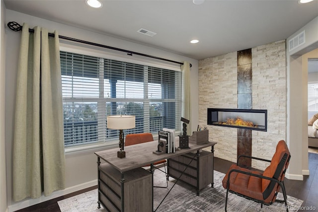 office area featuring a wealth of natural light, a stone fireplace, and hardwood / wood-style floors