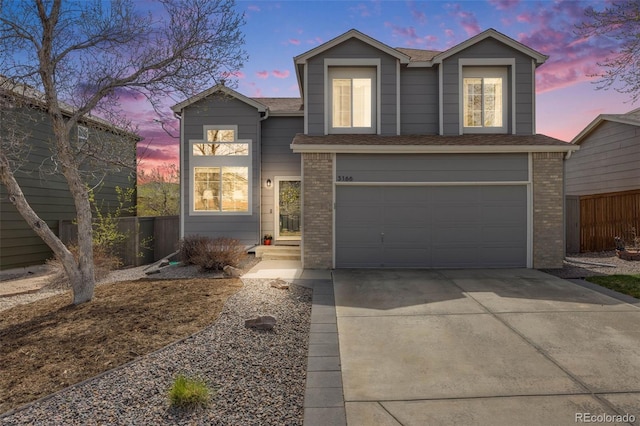 traditional home with driveway, a shingled roof, an attached garage, fence, and brick siding