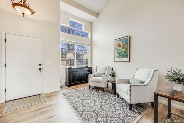 entryway with baseboards, a high ceiling, and light wood-style flooring