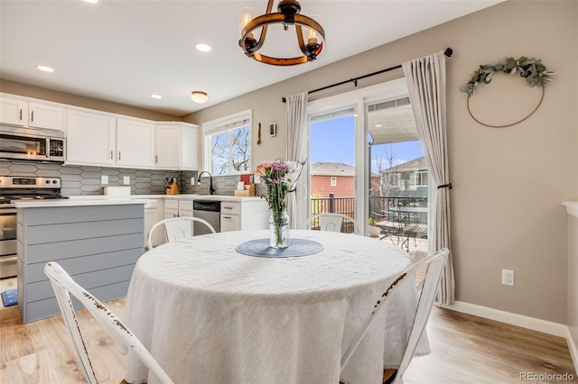 dining area with recessed lighting, light wood finished floors, baseboards, and an inviting chandelier