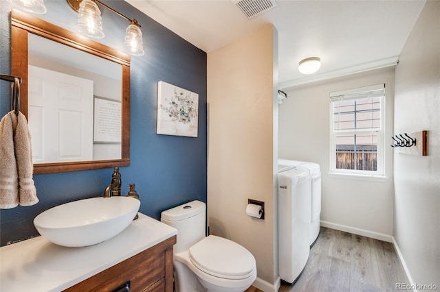bathroom featuring wood finished floors, visible vents, vanity, baseboards, and separate washer and dryer