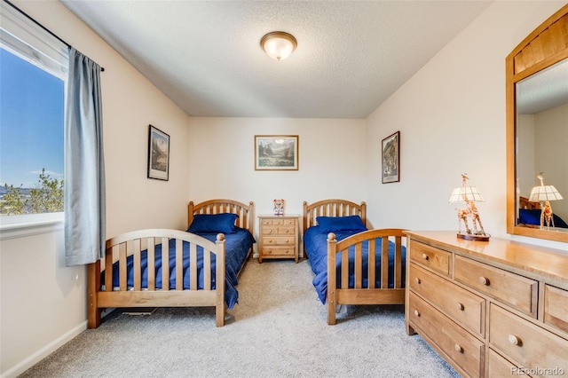 bedroom with light colored carpet, baseboards, multiple windows, and a textured ceiling