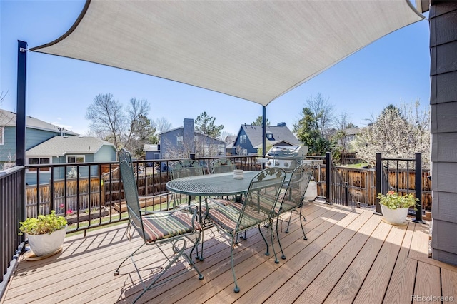 wooden deck with a residential view, fence, and outdoor dining space