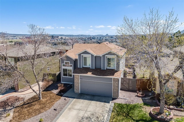 traditional home with an attached garage, a shingled roof, concrete driveway, and fence