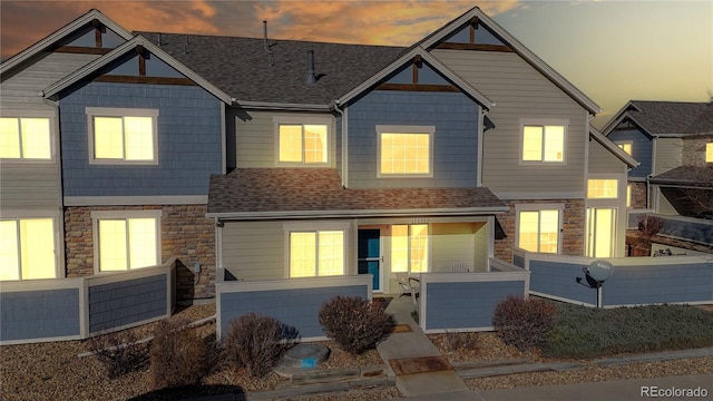 view of front of house featuring a fenced front yard, stone siding, and a shingled roof