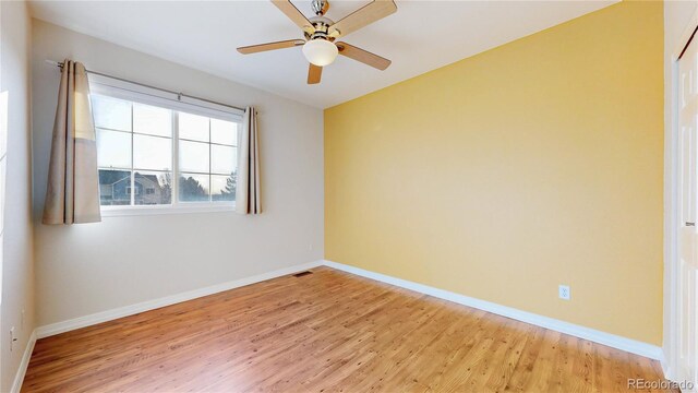 spare room featuring a ceiling fan, light wood-style floors, visible vents, and baseboards