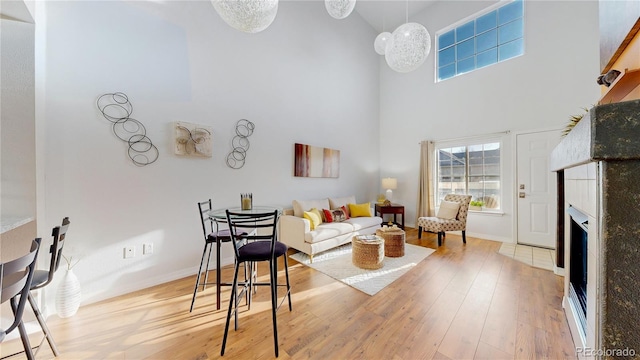 living room with a fireplace, a high ceiling, wood finished floors, and baseboards