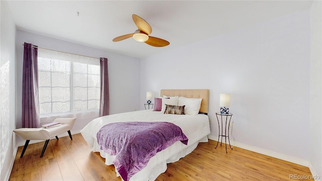 bedroom featuring baseboards, light wood-type flooring, and ceiling fan