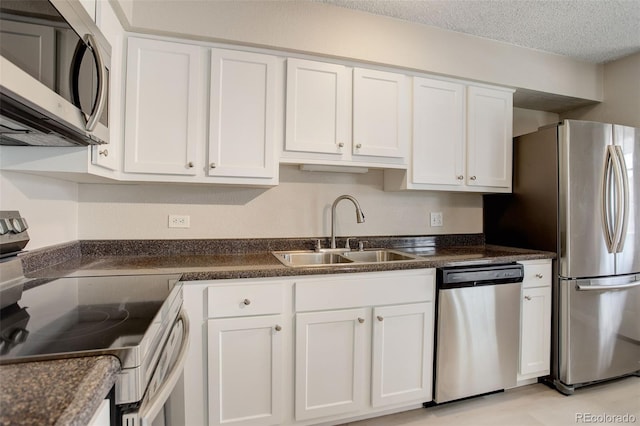 kitchen featuring a sink, stainless steel appliances, white cabinets, a textured ceiling, and dark countertops