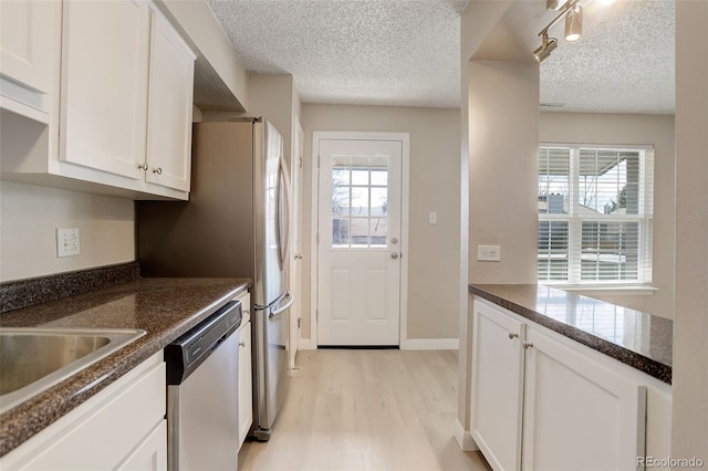 kitchen featuring baseboards, light wood finished floors, white cabinets, a textured ceiling, and stainless steel dishwasher