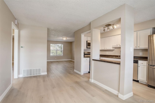 kitchen with visible vents, light wood-style floors, appliances with stainless steel finishes, white cabinetry, and dark countertops