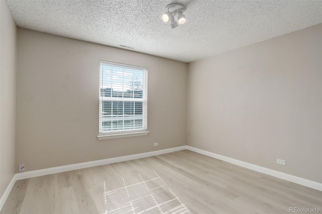 empty room featuring wood finished floors, baseboards, and a textured ceiling