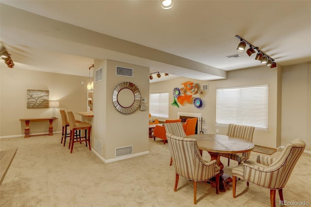 dining space featuring rail lighting, carpet flooring, and visible vents