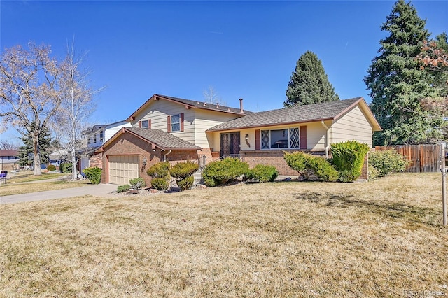 tri-level home with an attached garage, brick siding, fence, driveway, and a front yard