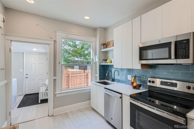 493 S Lincoln St, Denver, CO 80209 - kitchen with tasteful backsplash, open shelves, a sink, stainless steel appliances, and light countertops