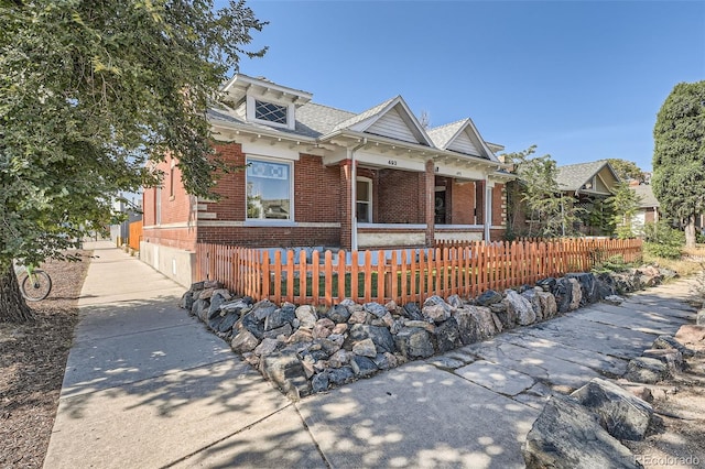 493 S Lincoln St, Denver, CO 80209 - view of front of home featuring covered porch, brick siding, and a fenced front yard