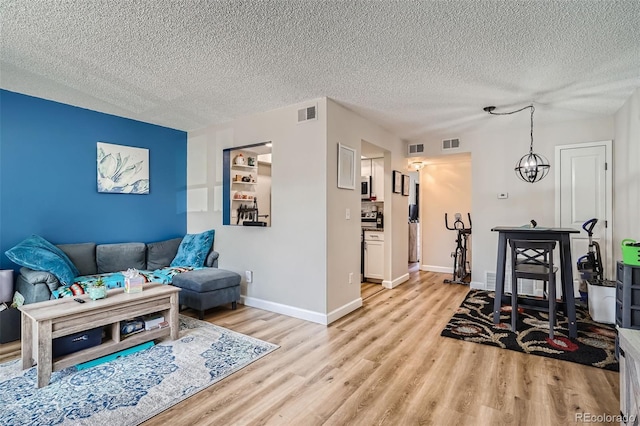 living room featuring light wood-type flooring, a textured ceiling, and a chandelier