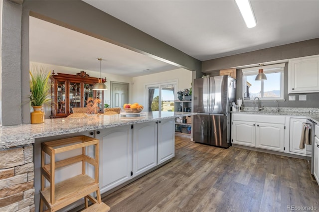 11170 Peaceful Valley Rd, Colorado Springs, CO 80925 - kitchen with freestanding refrigerator, white cabinetry, dark wood finished floors, light stone counters, and pendant lighting