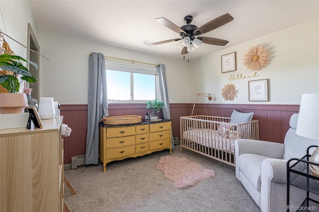 11170 Peaceful Valley Rd, Colorado Springs, CO 80925 - bedroom featuring a baseboard heating unit, wainscoting, a crib, carpet flooring, and wooden walls