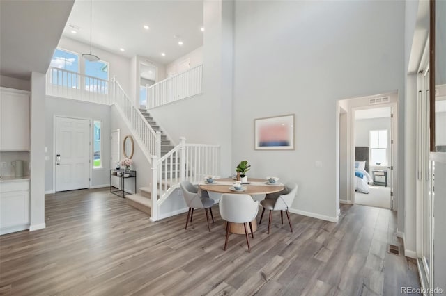 entrance foyer with wood finished floors, visible vents, baseboards, a high ceiling, and stairs