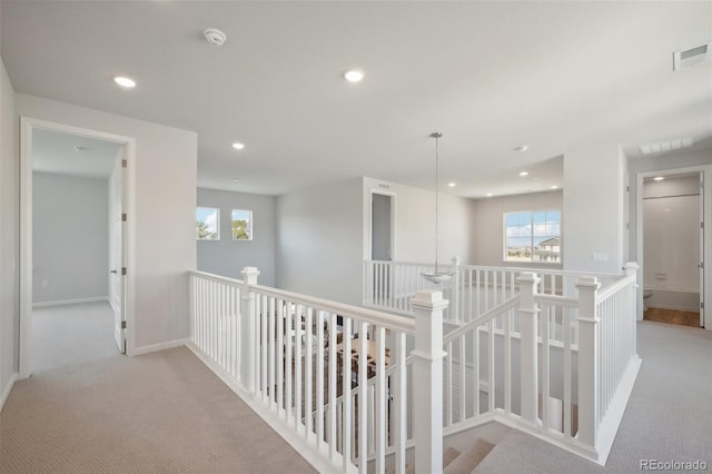 hall featuring visible vents, baseboards, recessed lighting, carpet flooring, and an upstairs landing