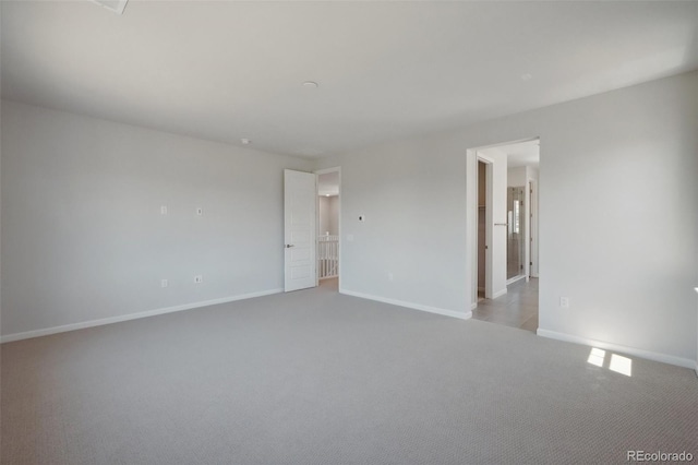 spare room featuring carpet and baseboards