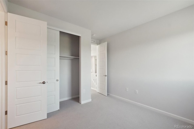 unfurnished bedroom featuring light colored carpet, a closet, and baseboards