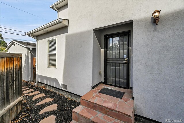 1431 Tamarac St, Denver, CO 80220 - property entrance with stucco siding, visible vents, and fence