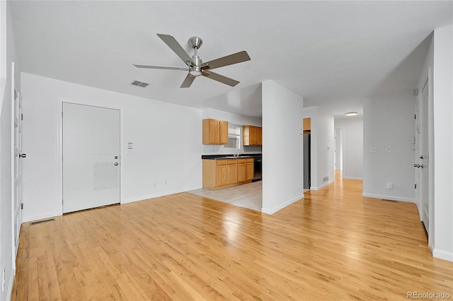 unfurnished living room featuring ceiling fan, sink, and light wood-type flooring