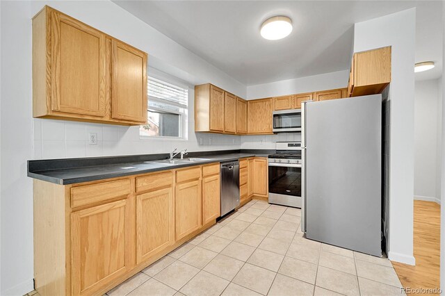 1431 Tamarac St, Denver, CO 80220 - kitchen featuring a sink, stainless steel appliances, decorative backsplash, light brown cabinets, and dark countertops