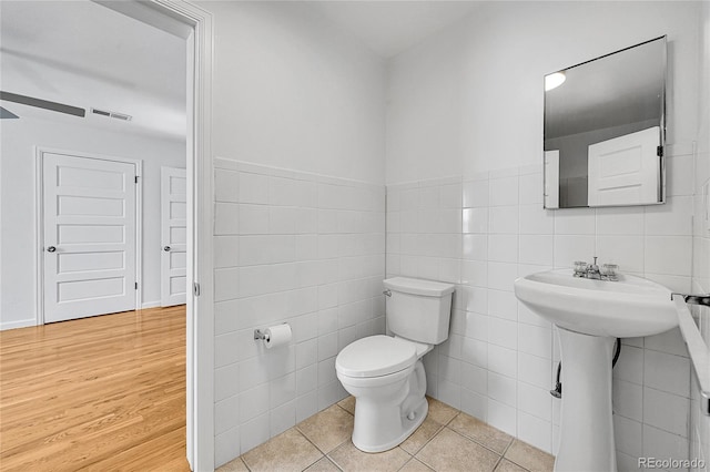 bathroom with toilet, hardwood / wood-style flooring, and tile walls