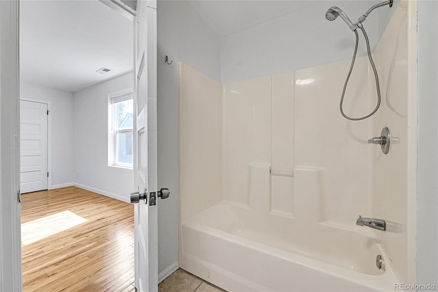 bathroom with hardwood / wood-style flooring and bathing tub / shower combination