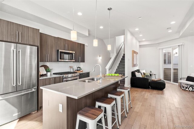 kitchen with a sink, a kitchen bar, open floor plan, high quality appliances, and an island with sink