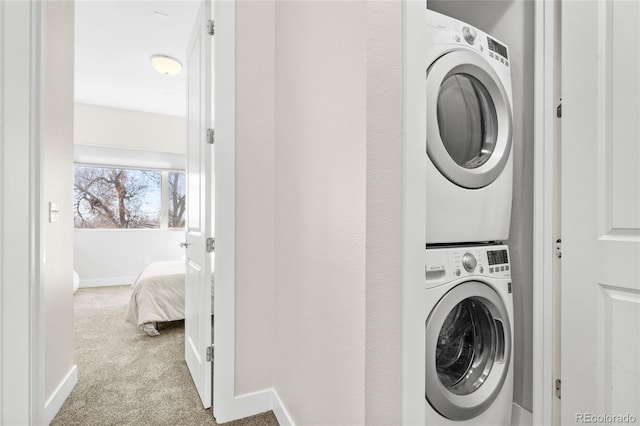 clothes washing area with carpet, baseboards, and stacked washer and dryer