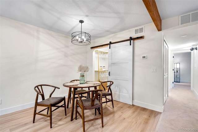 201 Wright St Unit 106, Lakewood, CO 80228 - dining room featuring a barn door, beam ceiling, baseboards, light wood-style floors, and a chandelier