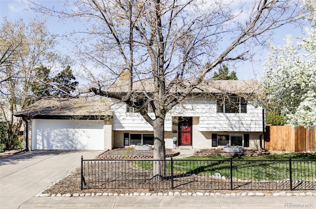 bi-level home with brick siding, a fenced front yard, concrete driveway, and an attached garage