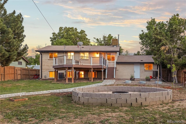 13055 E Dakota Ave, Aurora, CO 80012 - back of house at dusk with brick siding, a wooden deck, stairway, and a fire pit