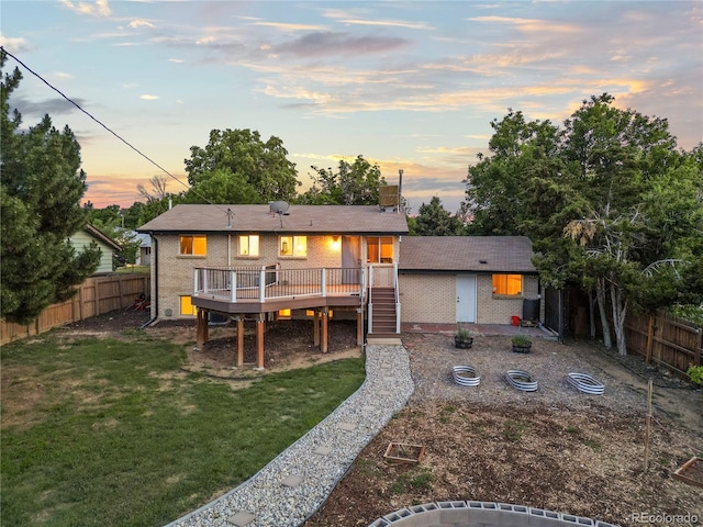 13055 E Dakota Ave, Aurora, CO 80012 - back of property at dusk with brick siding, a wooden deck, a fenced backyard, and stairway