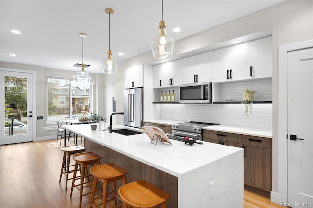 2179 S Bannock St, Denver, CO 80223 - kitchen with appliances with stainless steel finishes, a sink, a breakfast bar, light wood-type flooring, and modern cabinets
