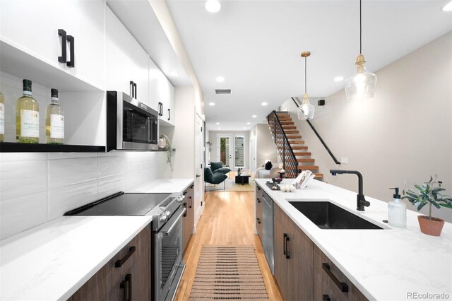 2179 S Bannock St, Denver, CO 80223 - kitchen with appliances with stainless steel finishes, a sink, recessed lighting, light wood-style flooring, and white cabinetry