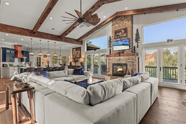 living room featuring a fireplace, beam ceiling, dark hardwood / wood-style flooring, high vaulted ceiling, and ceiling fan