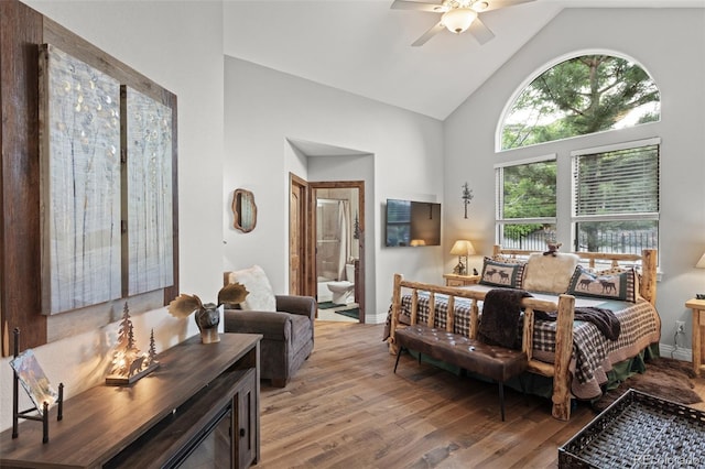 bedroom with ceiling fan, ensuite bathroom, wood-type flooring, and high vaulted ceiling