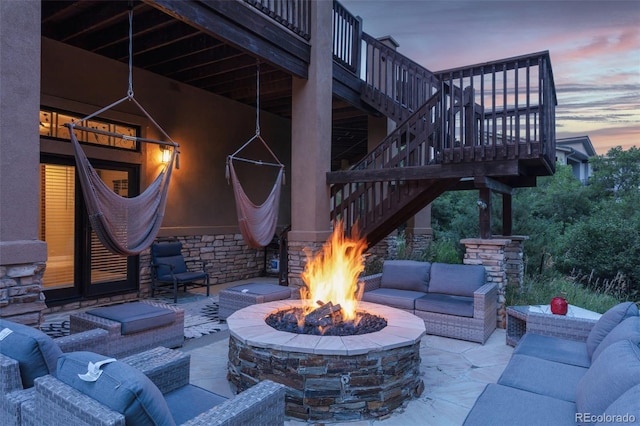 patio terrace at dusk featuring an outdoor living space with a fire pit and a wooden deck