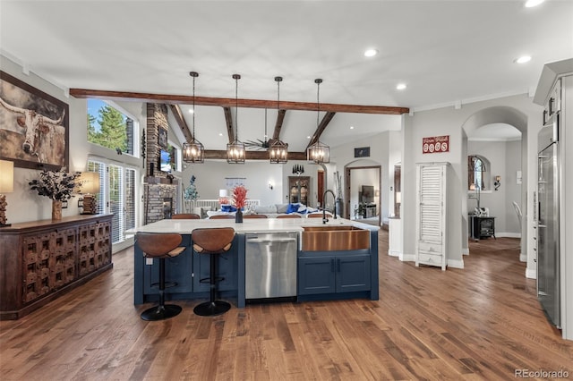 kitchen with appliances with stainless steel finishes, dark hardwood / wood-style floors, pendant lighting, sink, and blue cabinets