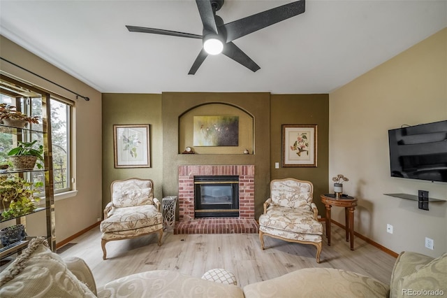 living room featuring wood finished floors, baseboards, ceiling fan, and a fireplace
