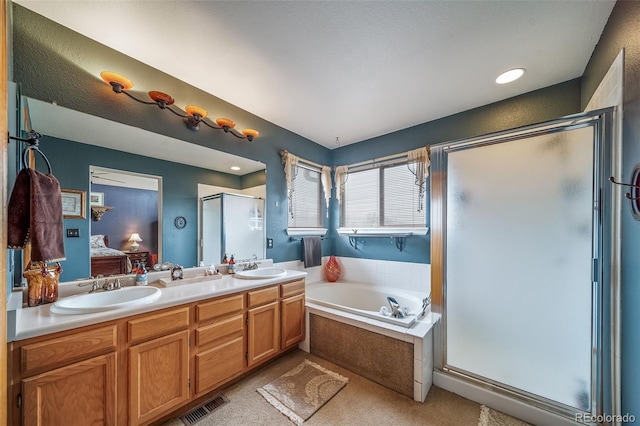 ensuite bathroom with a garden tub, ensuite bathroom, a shower stall, and a sink