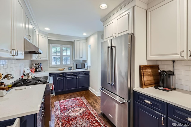1224 Glencoe St, Denver, CO 80220 - kitchen featuring appliances with stainless steel finishes, blue cabinets, under cabinet range hood, white cabinetry, and recessed lighting