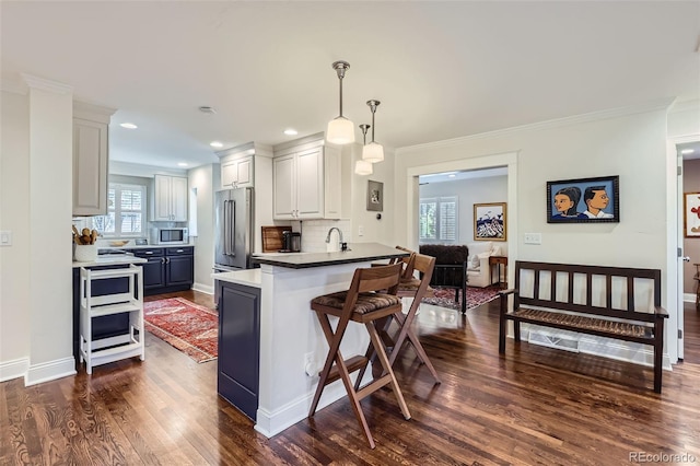 1224 Glencoe St, Denver, CO 80220 - kitchen featuring a peninsula, appliances with stainless steel finishes, decorative backsplash, a breakfast bar, and dark wood finished floors