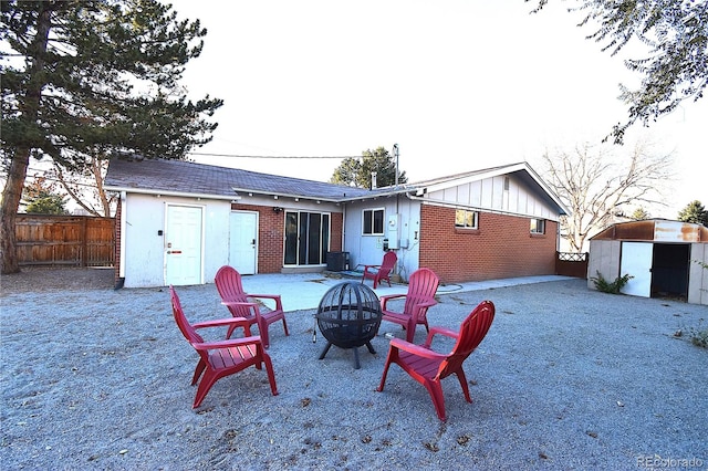 rear view of property with a shed and an outdoor fire pit