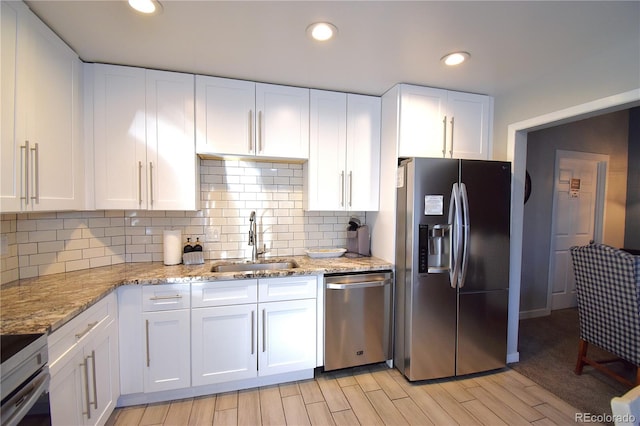 kitchen with white cabinets, sink, light hardwood / wood-style flooring, light stone countertops, and stainless steel appliances